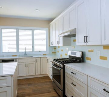 A newly remodeled kitchen featuring white cabinets and backsplashes accented with yellow tiles.