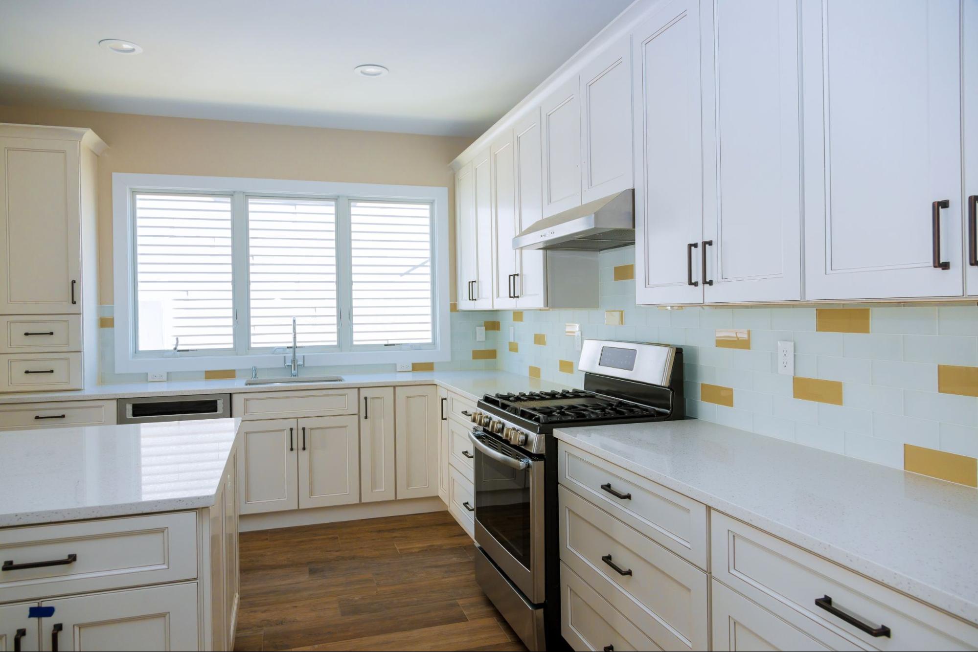 A newly remodeled kitchen featuring white cabinets and backsplashes accented with yellow tiles.