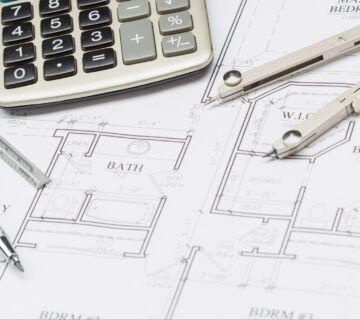 Calculator and drafting tools on bathroom plans showing elements that affect the average cost to remodel a bathroom.