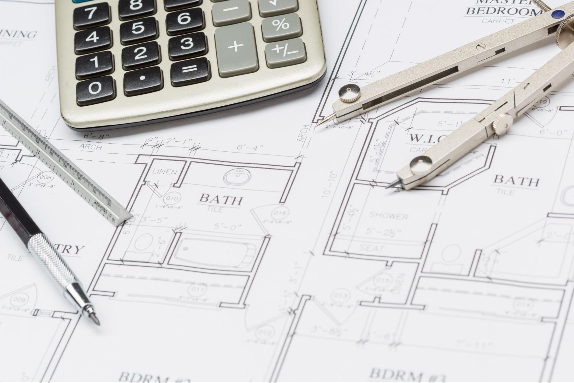 Calculator and drafting tools on bathroom plans showing elements that affect the average cost to remodel a bathroom.