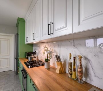 Modern kitchen remodel featuring green and white design with marble walls.