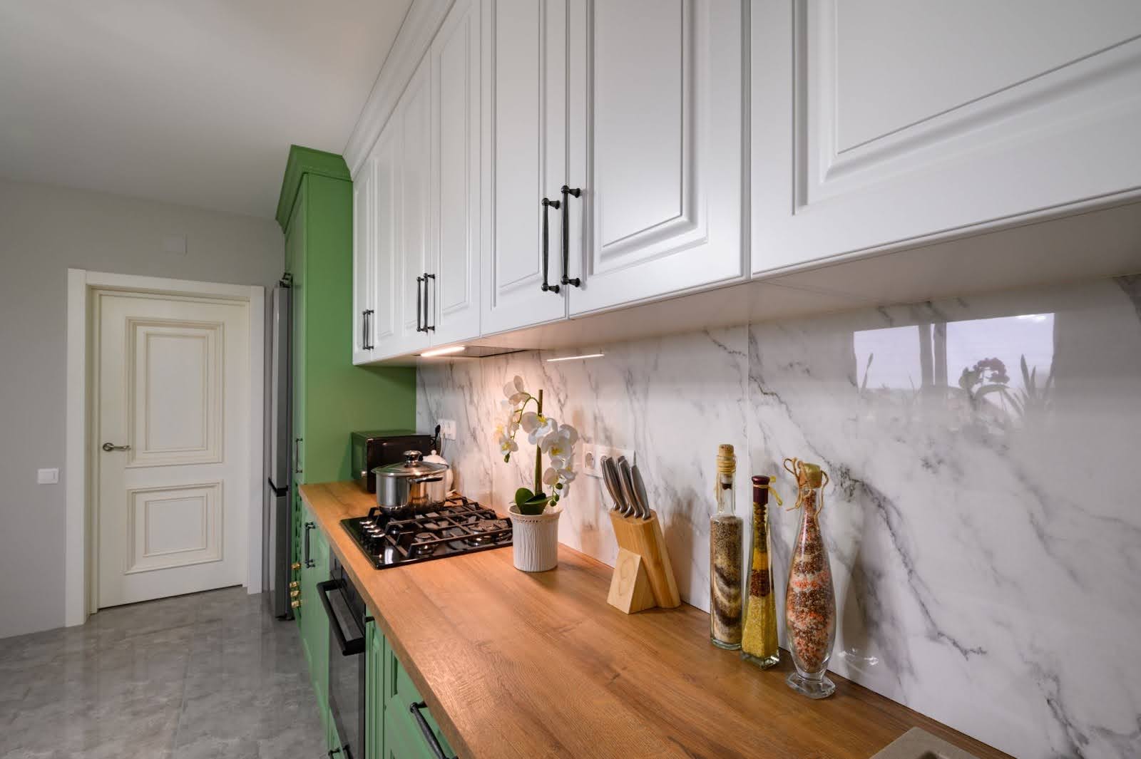 Modern kitchen remodel featuring green and white design with marble walls.