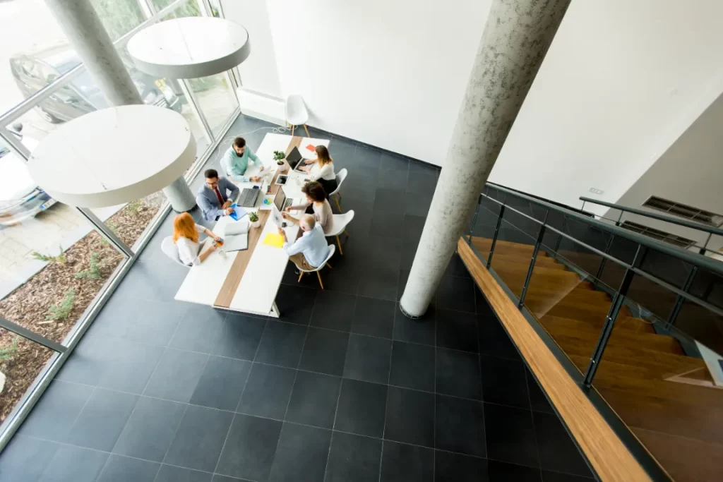 Overhead shot of a meeting taking place at a table on dark porcelain flooring.