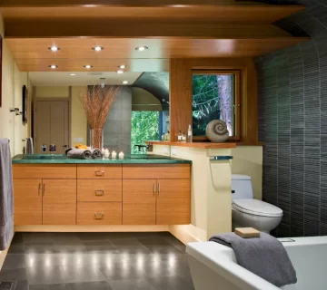 Wide shot of a luxurious bathroom with natural wood tones and green tile.