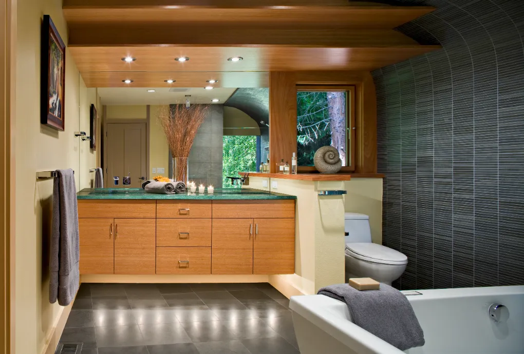 Wide shot of a luxurious bathroom with natural wood tones and green tile.