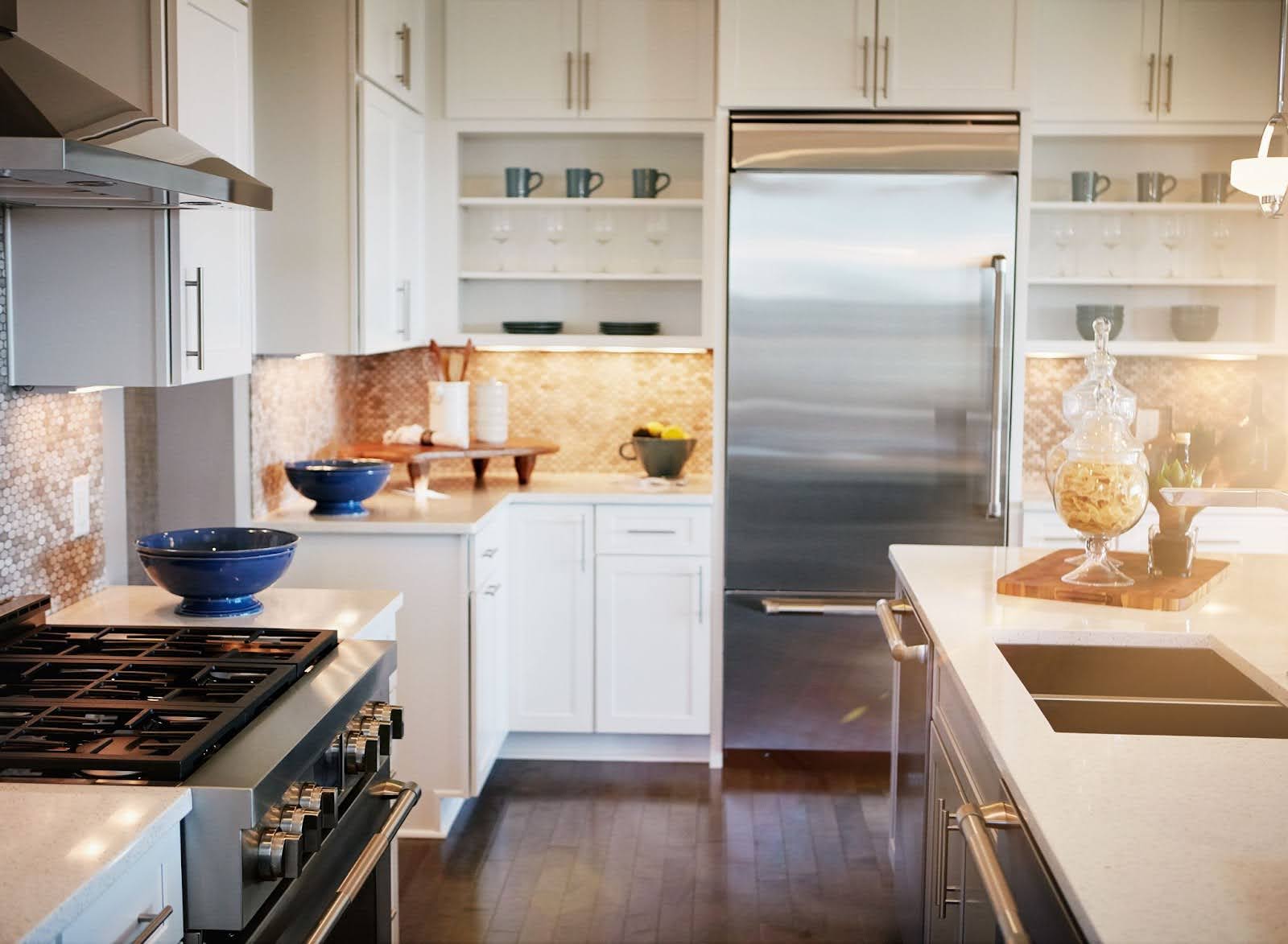 A side view of a modern kitchen that has white countertops and cabinets.