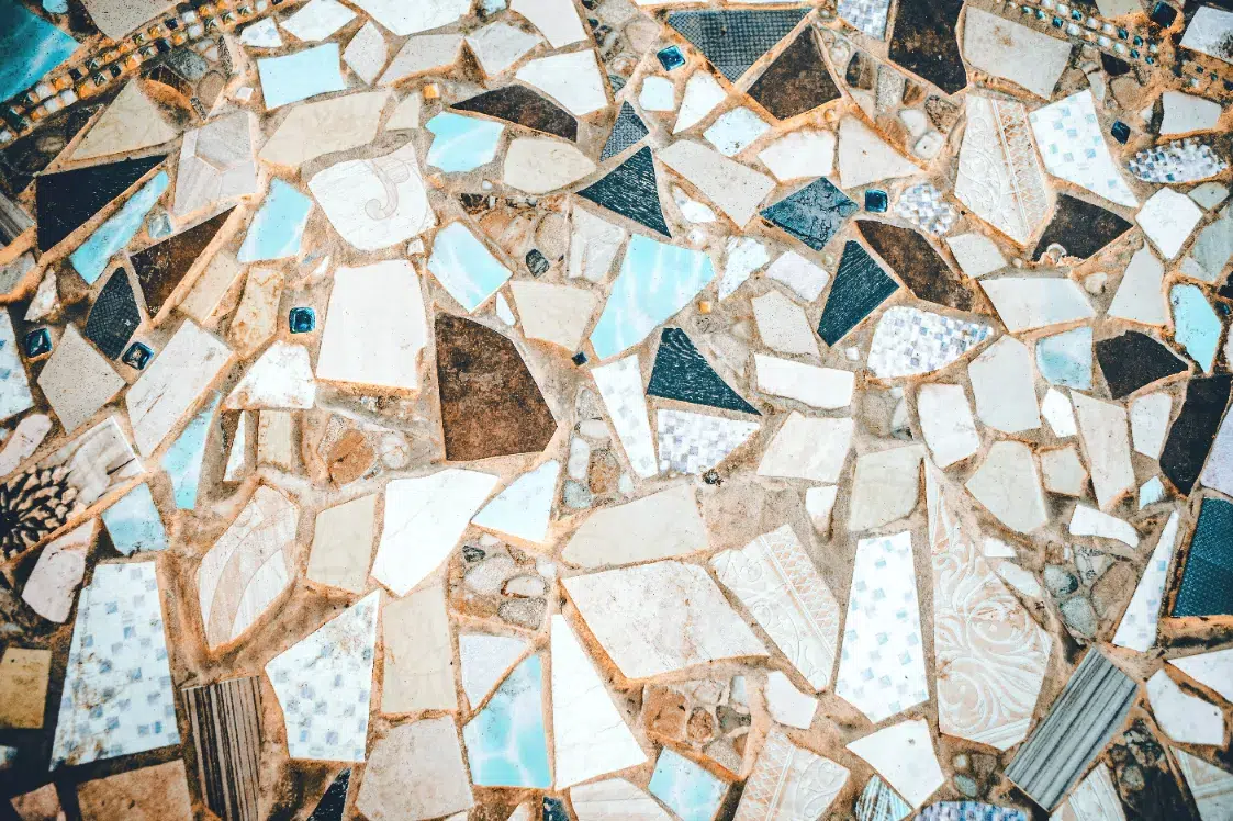 A close up of a mosaic tile floor with white and blue tiles.
