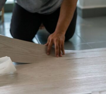 A man installs a piece of waterproof vinyl flooring in his home 