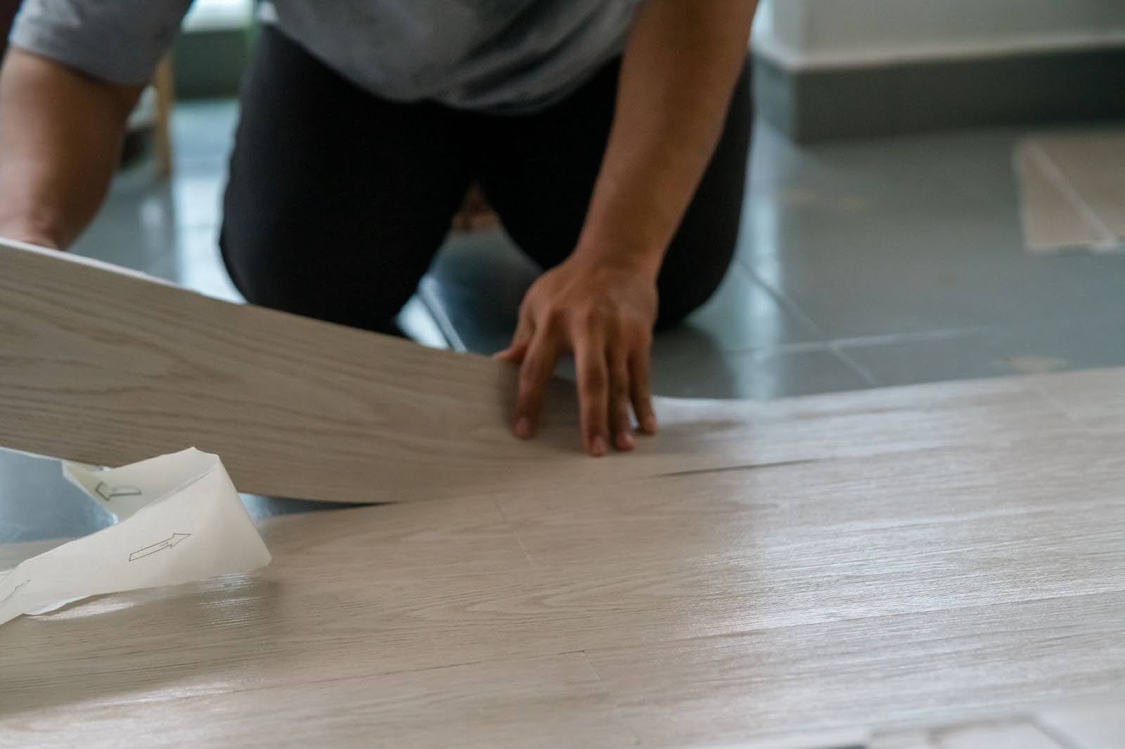 A man installs a piece of waterproof vinyl flooring in his home.